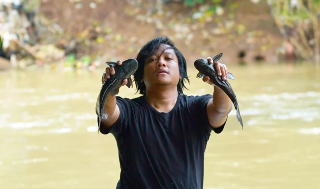 Relawan menangkap ikan sapu-sapu di Sungai Ciliwung dengan latar air keruh Jakarta